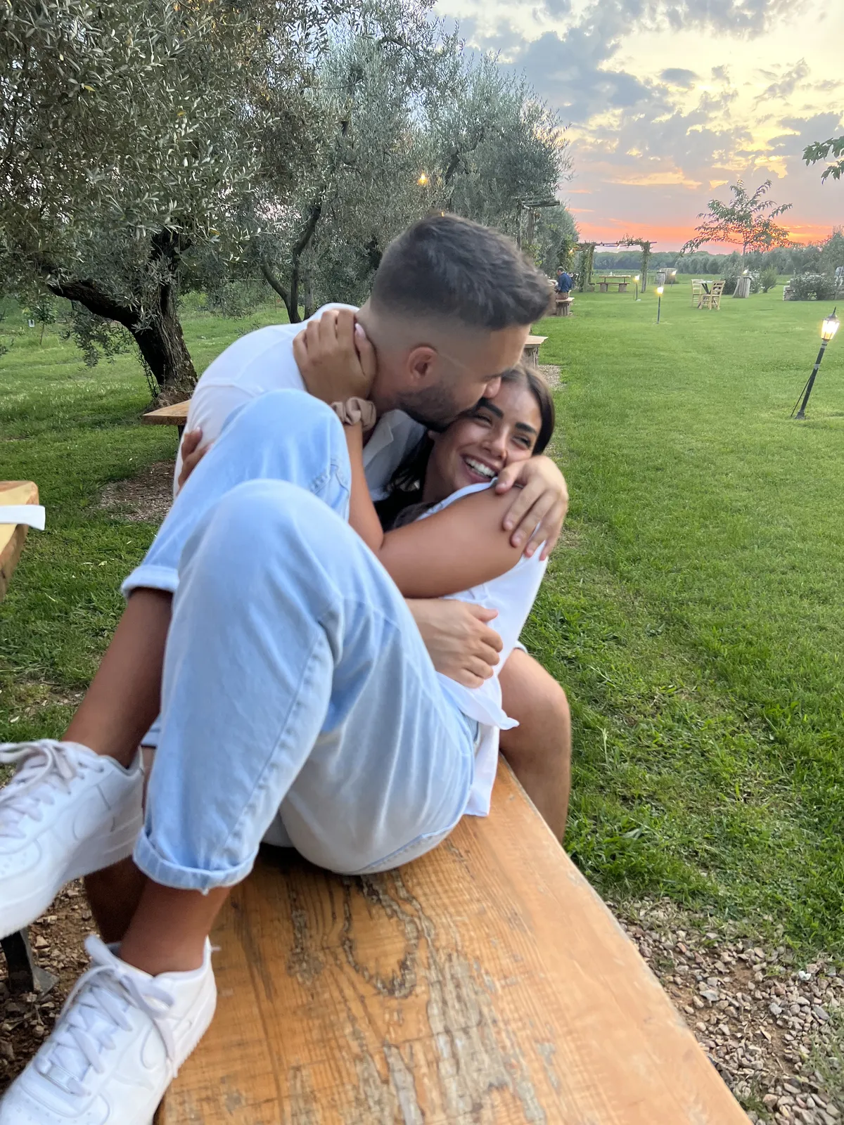 Davide e Marika abbracciati in un uliveto al tramonto